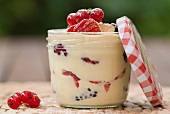A vanilla custard dessert with fresh berries in a screw-top jar