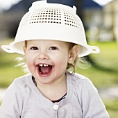 A little girl with a plastic colander on her head