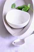 White crockery, a dessert spoon and mint leaves