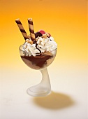 Chocolate ice cream sundae with cream, hazelnuts, nut brittle and rolled wafers