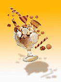 An exploding ice cream sundae with vanilla and nut ice creams, cream, amarettini biscuits, wafers, nuts, mini meringues and butterscotch sauce