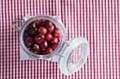 Cranberries in a preserving jar on a gingham tablecloth