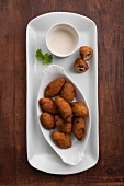 Kibbeh (North African bulgur dumplings) filled with nuts, with a tahini dressing