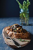 Mushroom, Sausage and Thyme Crostini on a Small Cutting Board; Fork