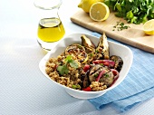 Warm Quinoa Salad with Grilled Eggplant , Red Onion and Lemon in a White Bowl; Olive Oil, Parsley and Lemons in Background