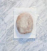 Brot auf Papier und Marmorplatte mit Mehl