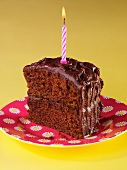 A slice of devil's food cake (chocolate layer cake, USA) with a birthday candle