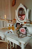 Silver-plated hand mirror, perfume bottles and rose on antique, shabby-chic dressing table