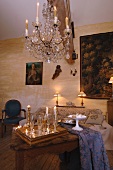 Traditioneller Wohnraum - Kronleuchter mit brennenden Kerzen über Tisch und gefüllte Champagnergläser auf Tablett