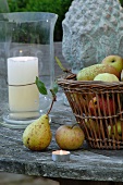 Basket of apples and pears on faded terrace table; large lantern in background