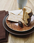 A slice of Baumkuchen (German layer cake) and an envelope with writing on it, on a dish with a reticulated design