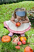 A blond girl with a Swiss apple, pears and pumpkins in the garden