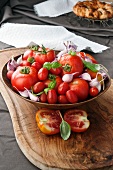 Assorted tomatoes and garlic cloves in an olive-wood bowl on an olive-wood board