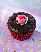 A chocolate cupcake with a sugar flower