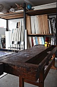 Old workbench in front of shelves of wooden elements in attic workshop