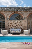 Terrace with white outdoor furniture and pool next to Mediterranean house