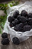 Fresh blackberries in and beside a glass bowl