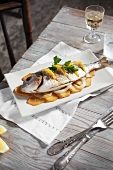 Grilled gilt-head bream with oranges on top of potato slices