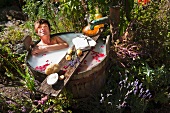 A woman having a milk bath in a wooden tub in the garden