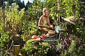 Frau putzt Obst und Gemüse am Brunnen im Garten