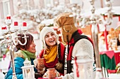 Zwei Frauen und ein Mann unterhalten sich bei einem Weihnachtsmarkt
