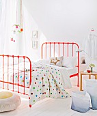 Orangerotes Metallbett und Decke mit bunten Punkten in lichtdurchflutetem Schlafzimmer
