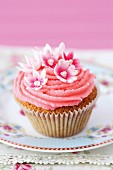 A cupcake decorated with pink frosting and sugar flowers