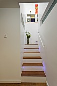 Schmaler Treppenaufgang mit Holz Trittstufen und Blumenvase auf Podest