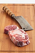 A piece of beef hock and a cleaver on a chopping board