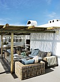 Südländisches Ferienhaus mit Rattanmöbeln unter Pergola auf Terrasse