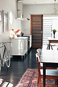Kleine Küchenzeile, zwei Esstische und ein Rennrad im offenen Wohnraum
