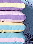 Gestapelte Polster mit verschiedenfarbigen Streifenbezug in Pastelltönen