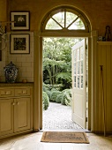 Blick in den Garten durch eine nach aussen geöffnete, verglaste Holztür; stilvolle Landhausküche in weichem Shaker-Beige