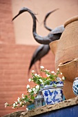 Potted plants with white flowers on step in front of terracotta pot and ornamental crane figures