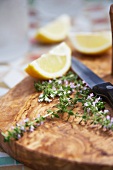 Fresh thyme and lemon wedges on a chopping board