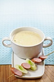 Creamy soup with a sausage and leek skewer