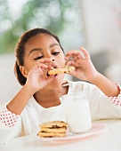 A girl eating a cookie with milk