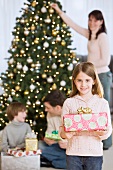 Girl holding Christmas gift in front of family