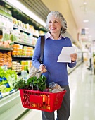 USA, New Jersey, Jersey City, Senior woman carrying shopping basket in supermarket