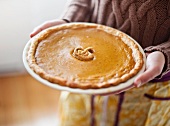 Close up of woman holding pumpkin pie