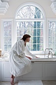 Woman in robe drawing bath