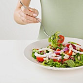 Close up of woman eating plate of salad