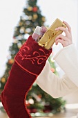 Woman stuffing gifts into Christmas stocking