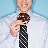 Businessman eating frosted donut