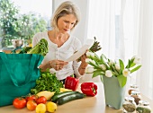 Frau mit Einkaufstasche und Gemüse in der Küche