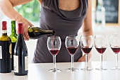 Frau schenkt Rotwein in Weingläsern ein