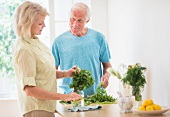 Älteres Paar bereitet Kräuter in der Küche vor