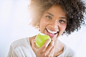 Junge Frau isst einen grünen Apfel