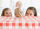 Sisters taking cookies from jar