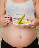 Schwangere Frau isst Essiggurken